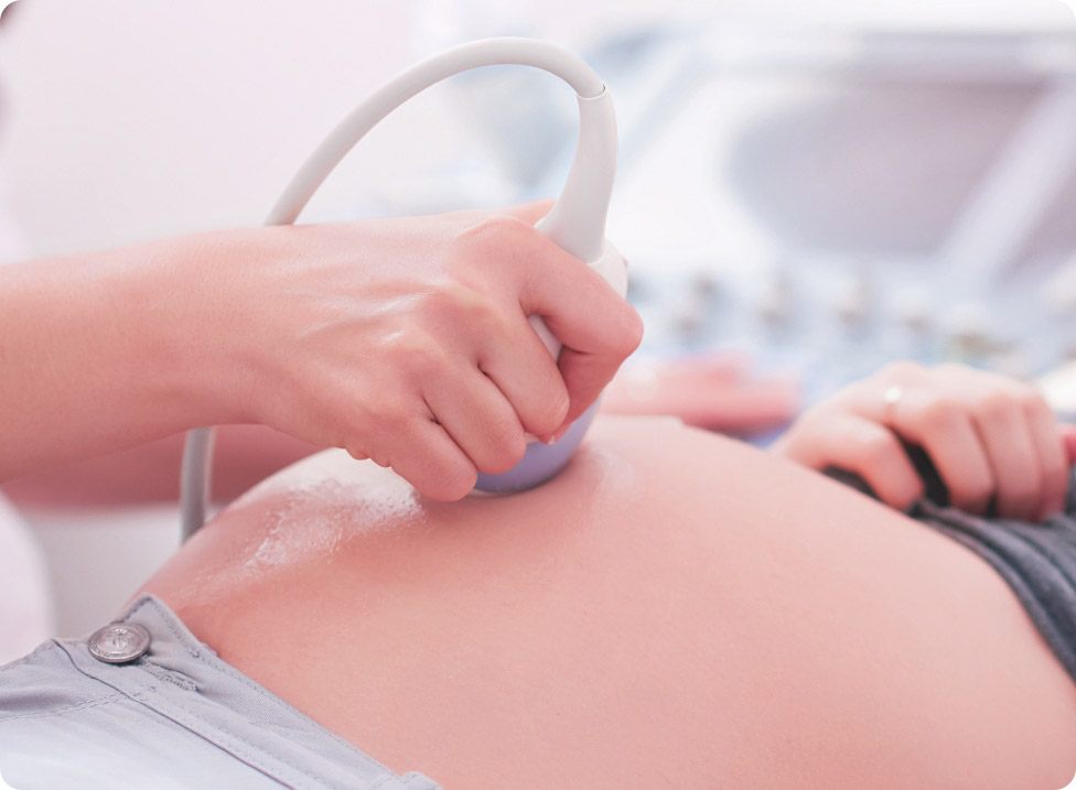 Hand hält Ultraschallsonde auf freiem Bauch einer liegenden Person